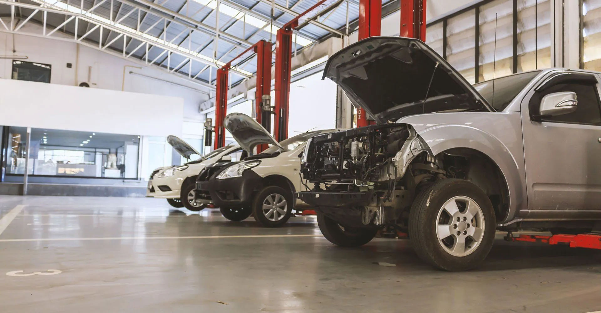 Repair bays with vehicles on lifts, one with its hood open