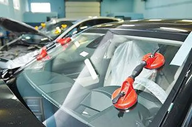 New windshield held in place with red suction cups during installation